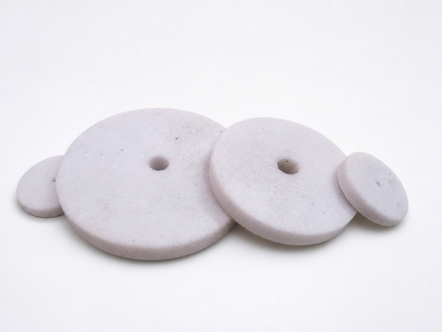 Circular oil stones and abrasive discs on a white studio background